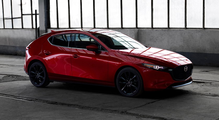 A red Mazda3 hatchback parked inside an industrial-style garage, showcasing its sleek design and sporty look at Middletown Mazda.