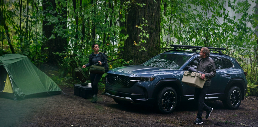 2026 Mazda CX-50 SUV at a forest campsite with roof rack and gear
